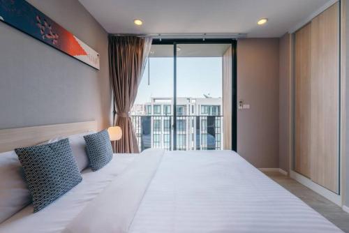 a bedroom with a large bed with a large window at Modern Condo in Nimman (F806) by Pimolplace in Chiang Mai