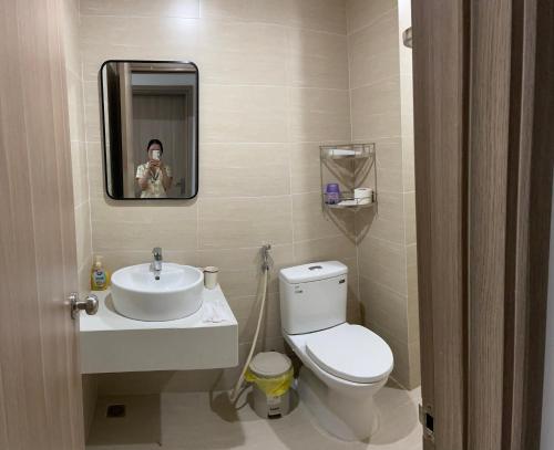 een vrouw die een foto neemt van een badkamer met toilet en wastafel bij Moon homestay, apartment Hue in Hue