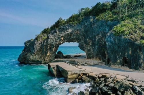 a beach with an arch in the rocks and the ocean at Condo de Avila in Boracay