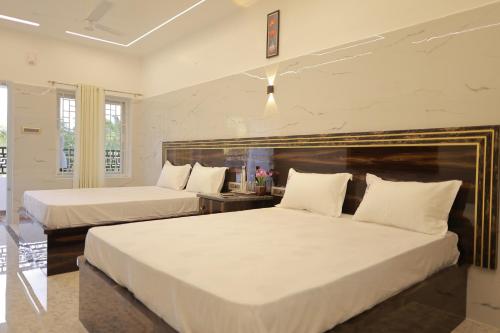 two beds in a hotel room with white sheets at HOTEL CYRIL in Kanyakumari