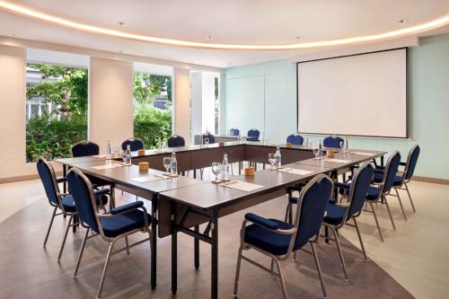 a conference room with a long table and chairs and a whiteboard at Grand Mercure Bali Seminyak in Seminyak