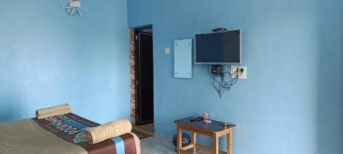 Cette chambre est dotée d'un mur bleu, d'une télévision et d'une table. dans l'établissement Poornima Beach Stay, à Gokarna