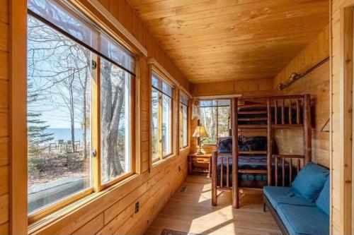 a cabin with windows and a blue couch and a bed at Lakefront Serenity 