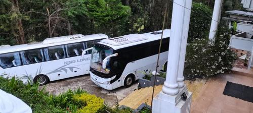 two white buses parked next to a house at Panorama Green View Hotel Nuwara Eliya in Nuwara Eliya