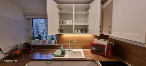 a kitchen with a sink and a microwave on a counter at 7-24 Self-Check-In - 120qm - 5 rooms - 2 bathrooms - kitchen - free parking - Yihapartment in Hannover