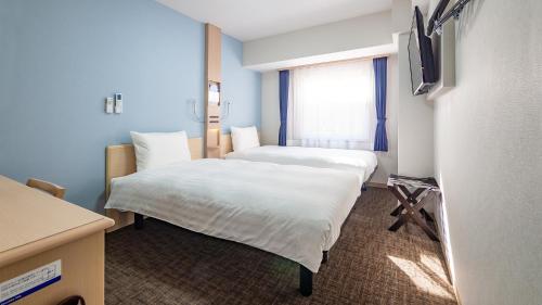a hotel room with two beds and a window at Toyoko Inn Tokyo Minami-machida in Machida