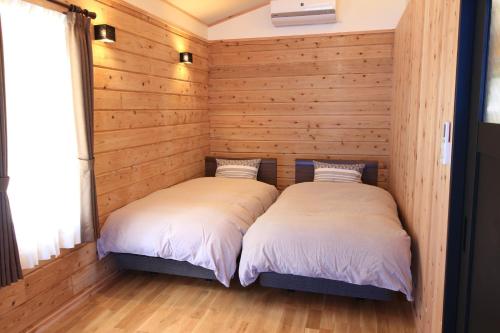 Yama-gu - House - Vacation STAY 52848v في Inawashiro: سريرين في غرفة بجدران خشبية