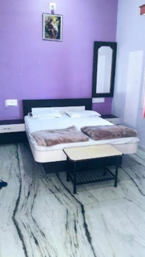 2 Betten in einem Zimmer mit lila Wänden in der Unterkunft Hotel Sai Krupa,Alirajpur 
