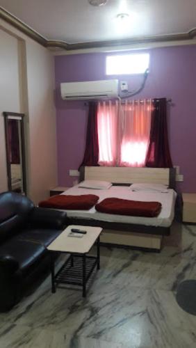 ein Schlafzimmer mit einem Bett, einem Sofa und einem Fenster in der Unterkunft Hotel Sai Krupa,Alirajpur 