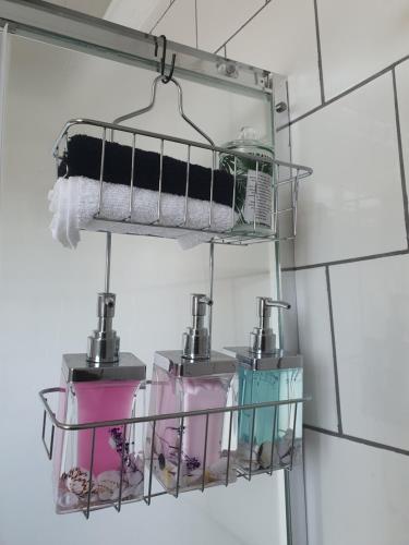 a metal rack with four different items in it in a bathroom at Mpucuko Guest House in Mtubatuba