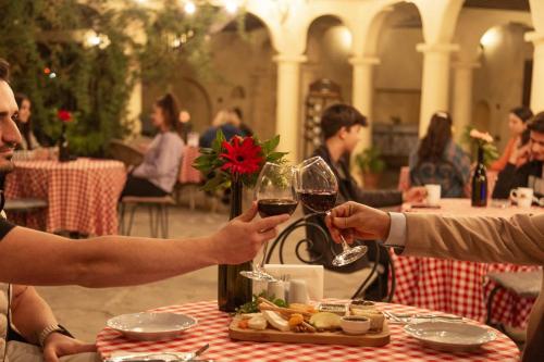 two people sitting at a table with glasses of wine at Anemon Hotel Kula in Kula