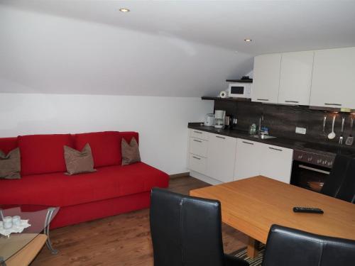 a living room with a red couch and a table at Apartment in Krimml with a balcony or terrace in Krimml