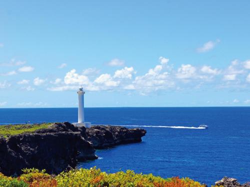 a lighthouse on a cliff in the ocean with a boat at Aqua Palace Chatan by Coldio Premium in Chatan