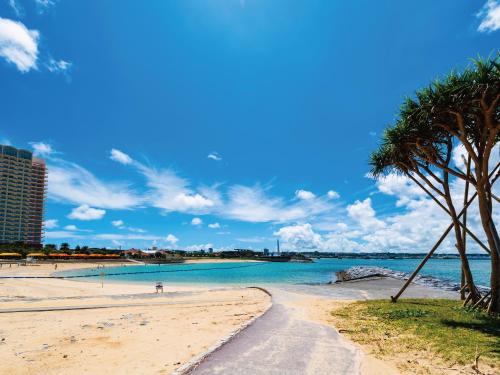 a beach with a palm tree and the ocean at Aqua Palace Chatan by Coldio Premium in Chatan