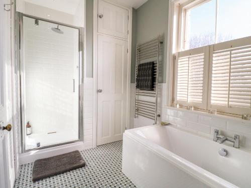een witte badkamer met een bad en een raam bij The Coach House in Grantham