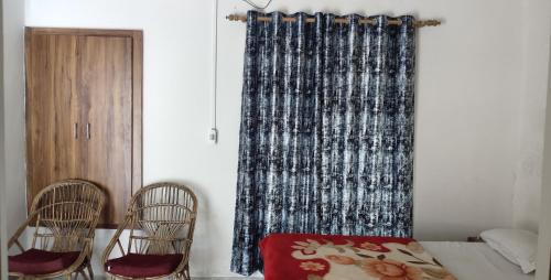 a bedroom with two chairs and a bed and a curtain at Govind Home Stay in Rishīkesh