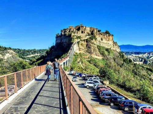 a group of people standing on a bridge with a castle on a mountain at La Semplicità del Borgo in Bagnoregio