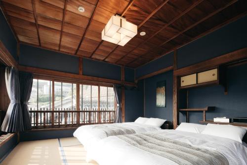 two beds in a room with blue walls and a window at LAMP Iki in Iki