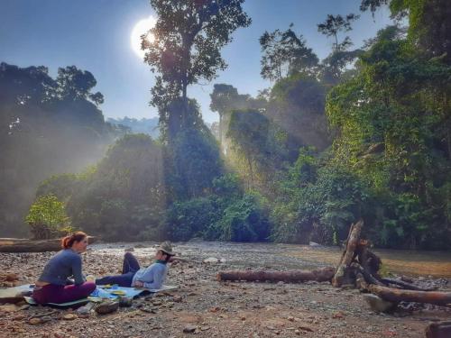 a group of people sitting on the shore of a river at eco trekking lodge Bar & tour's in Bukit Lawang