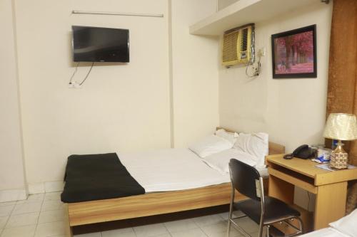 Habitación pequeña con cama y escritorio con ordenador. en Hotel Grand Amir International, en Dhaka