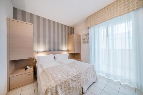 a bedroom with a bed and a large window at Hotel Europa Lignano in Lignano Sabbiadoro