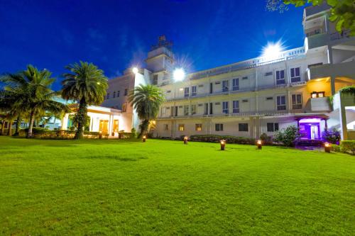 a large building with palm trees in front of it at Palette - Hotel Bon Sejour in Pondicherry