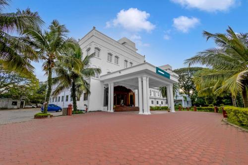 a white building with palm trees in front of it at Palette - Hotel Bon Sejour in Puducherry