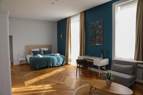 a bedroom with blue walls and a bed and a desk at Hôtel Les Séquoias in Ruy