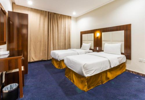 ein Hotelzimmer mit 2 Betten und einem TV in der Unterkunft Dar Hotel Suites in Dschidda