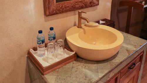 a bathroom with a sink and two bottles of water at Rumah Dharma Boutique Villa in Magelang