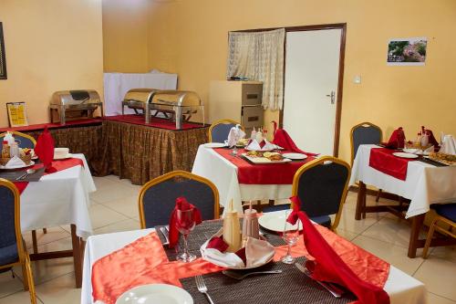 un comedor con mesas y sillas con servilletas rojas en Mango Lodge Zomba en Zomba