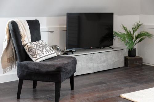 uma sala de estar com uma cadeira e uma televisão em Farringdon/St Pancras penthouse em Londres