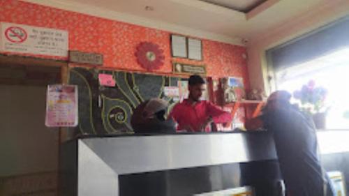 two people standing at a counter in a restaurant at Hotel Adhiraj Regency, Ashoknagar in Ashoknagar