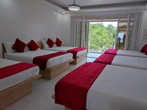 three beds in a room with a window at Seaview Emerald Adoces Beach Resort in Morong