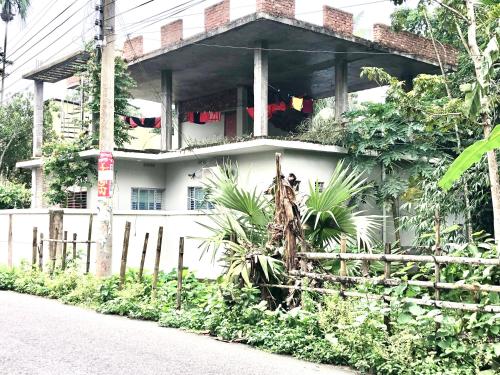 un bâtiment blanc avec des vêtements suspendus sur un balcon dans l'établissement Pirojpur Guest House, 