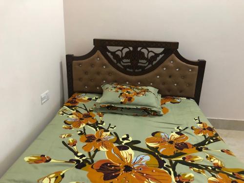 a bed with a floral comforter and two pillows at Pirojpur Guest House 