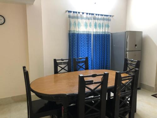 a dining room table with chairs and a blue curtain at Pirojpur Guest House 
