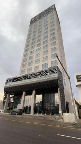 利雅德的住宿－Msharef almoden hotel فندق مشارف المدن，一座高大的建筑,前面有一辆汽车