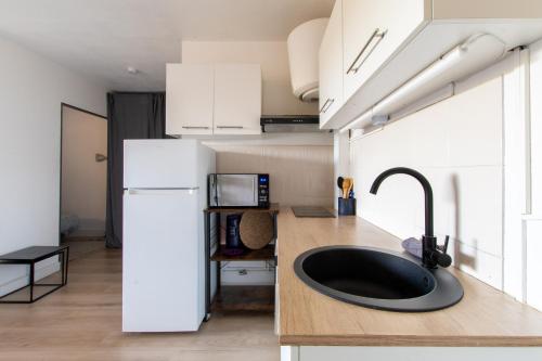 une cuisine avec un évier et un réfrigérateur blanc dans l'établissement L'étang de l'or *Joli T2 * Plage à 10 min * Proche Montpellier, à Carnon-Plage