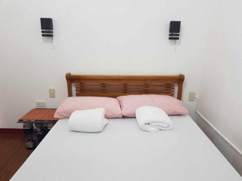 - un lit avec des oreillers roses et blancs dans l'établissement 2-storey house san pedro laguna belinda condotel 3, à San Pedro