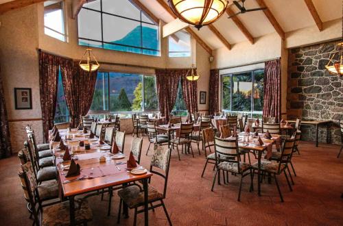 a dining room with tables and chairs and windows at Cathedral Peak Hotel in Winterton