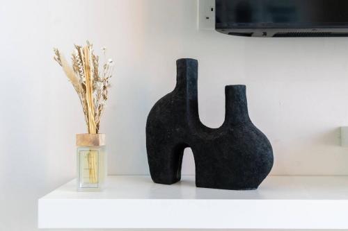 two black vases sitting on a shelf next to a jar at Crème De La Cozy 1 Bedroom in Dubai