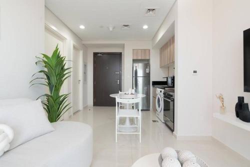 a white living room with a white couch and a kitchen at Crème De La Cozy 1 Bedroom in Dubai