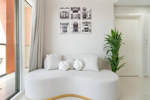 a white couch in a room with a plant at Crème De La Cozy 1 Bedroom in Dubai