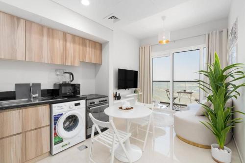 a kitchen with a washing machine and a dining room at Crème De La Cozy 1 Bedroom in Dubai