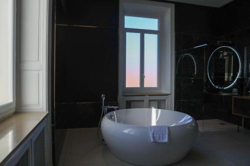 a large white tub in a bathroom with a window at Hôtel Les Séquoias in Ruy