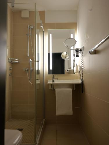 a bathroom with a shower and a sink and a mirror at Hotel du Nord Alster - auf der Uhlenhorst in Hamburg