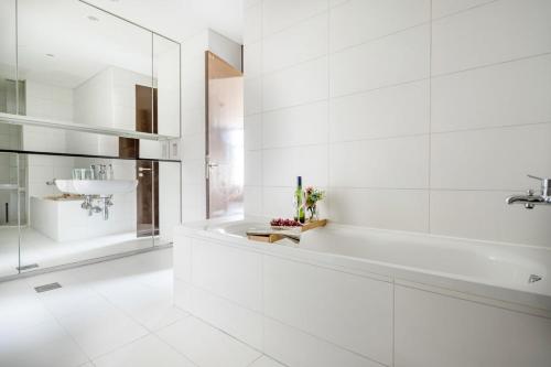 a white bathroom with a tub and a sink at Frank Porter - Index Tower in Dubai