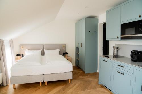 a bedroom with a white bed and a kitchen at Bob W Lübeck Old Town in Lübeck