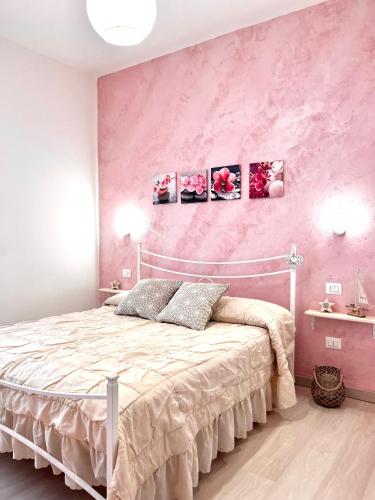 ein Schlafzimmer mit einem Bett mit einer rosa Wand in der Unterkunft Minù house in Scalea